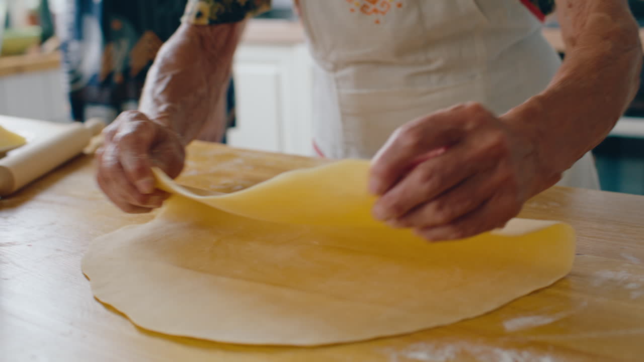 Primo piano di impasto steso piegato su un bancone da cucina in legno