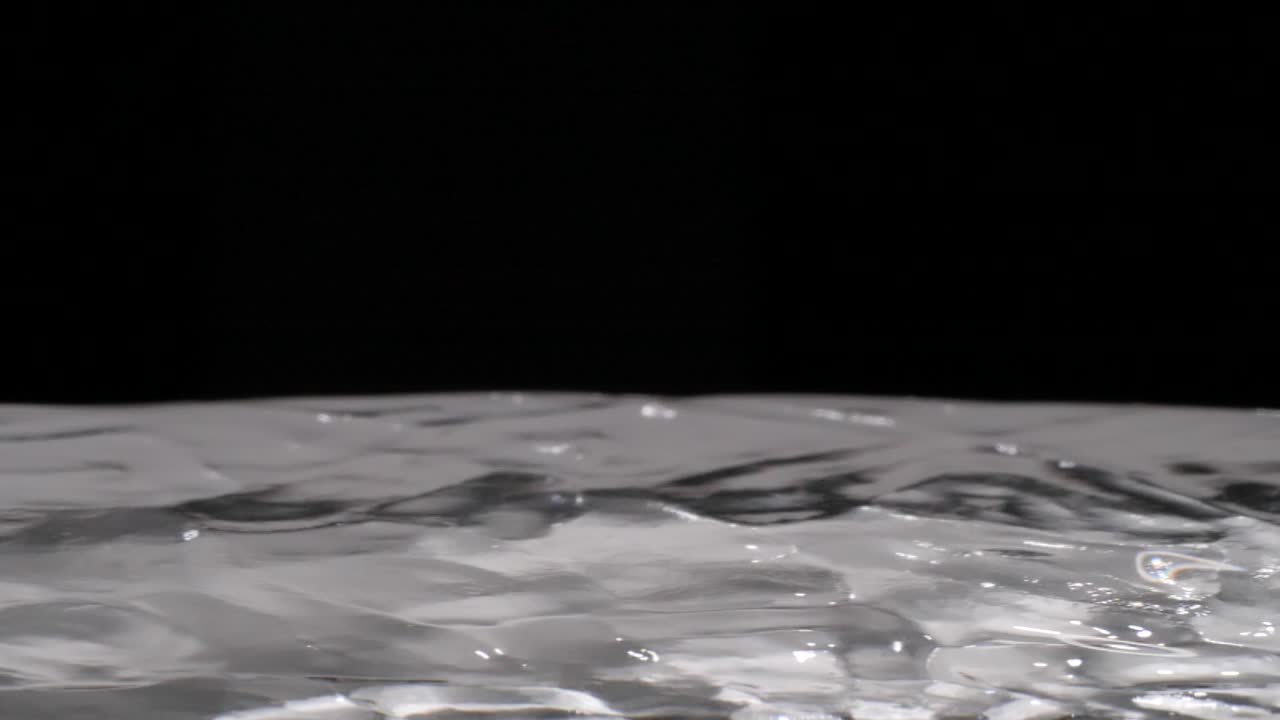 One water droplet bounces on clear liquid after breaking surface tension