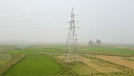 high voltage electric lines crossing a foggy farmland, a stark contrast of modern technology against the natural landscape