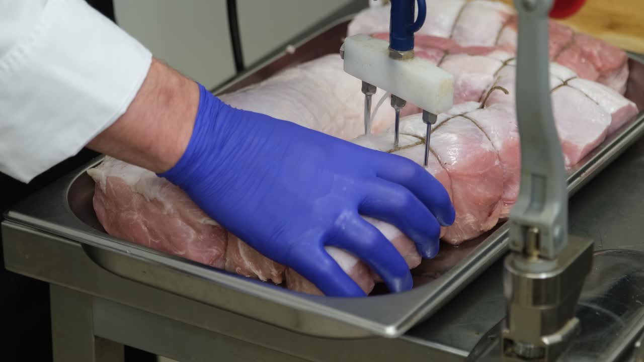 video della stagionatura della lonza di maiale cruda da parte di uno chef in guanti blu in cucina