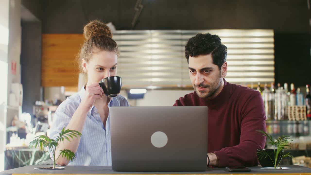 Una pareja trabajando en una computadora portátil en un café