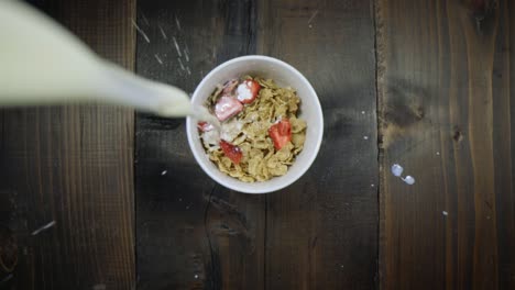 unique view of milk being poured into a bowl of cereal with dried strawberries