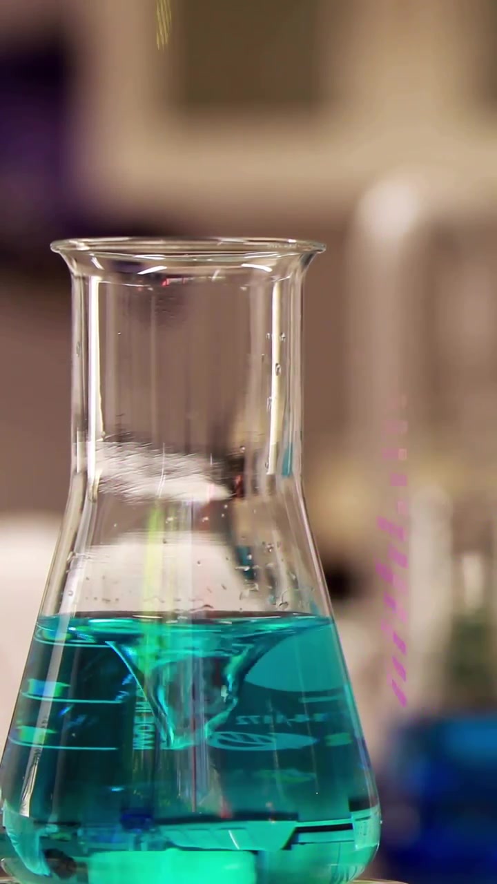 Video verticale: Fiaschetta su un banco che forma un vortice mentre overlay di codice appaiono, mostrando dati di laboratorio.