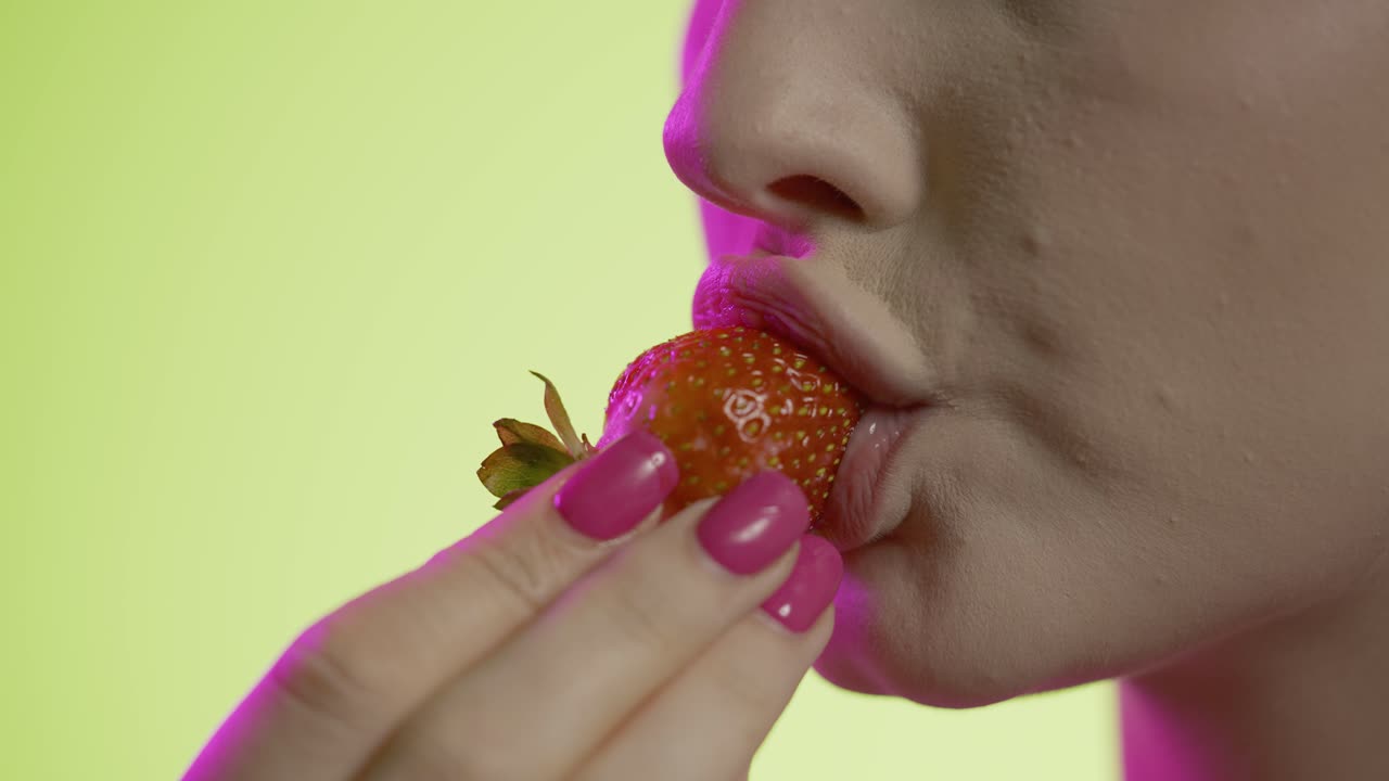 Woman eating a strawberry, side view mouth close up