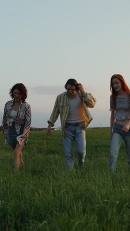 friends walking in a field at sunset