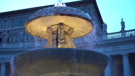 fuente frente al edificio del vaticano, roma, por la noche, iluminada con luz artificial amarilla.