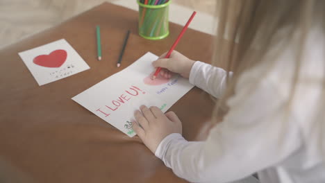 la piccola figlia disegna e colora il biglietto di auguri 1