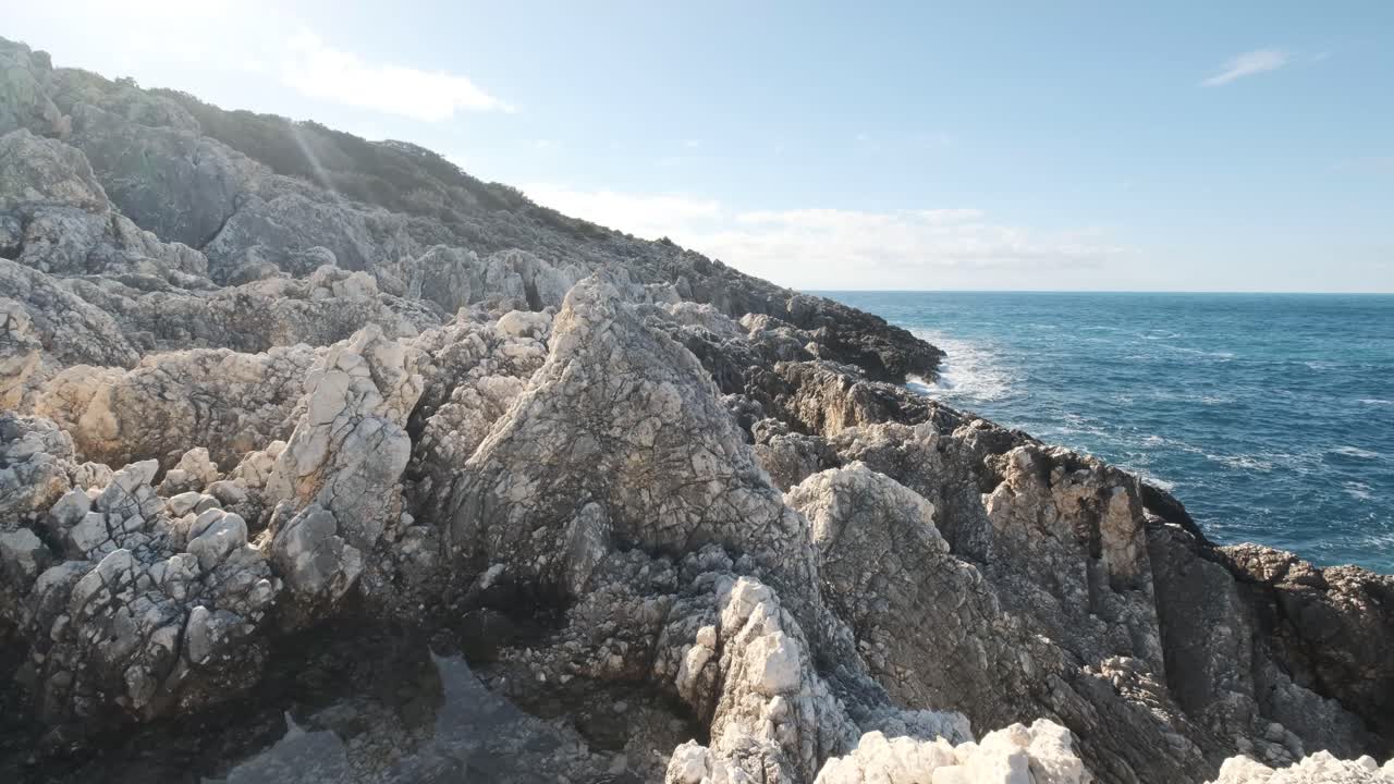 Rocce frastagliate sulla riva di un oceano blu intenso.