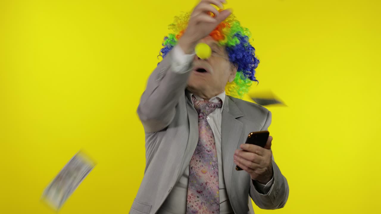 Uomo d'affari clown, libero professionista, capo, riceve un reddito mentre usa lo smartphone