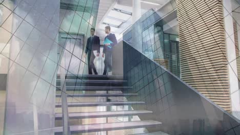 Animation-of-office-building-over-businessmen-talking-in-modern-office