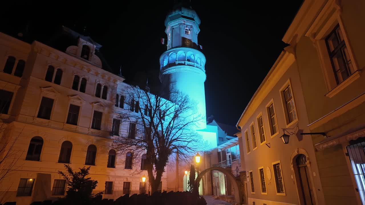 The Fire Tower in Sopron illuminated with vibrant light colors at night, creating a stunning view.