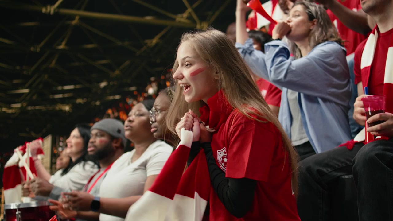 Giovane tifosa di calcio tesa che tiene una sciarpa rossa alla bocca
