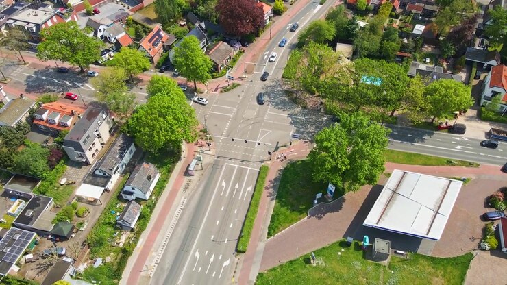 Jib down of busy intersection with cars and cyclists on sunny day
