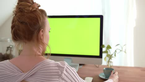 young women sitting in front of computer with green screen mock-up