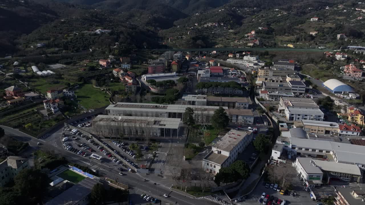 Savona university campus surrounded by hills on a clear sunny day, aerial view