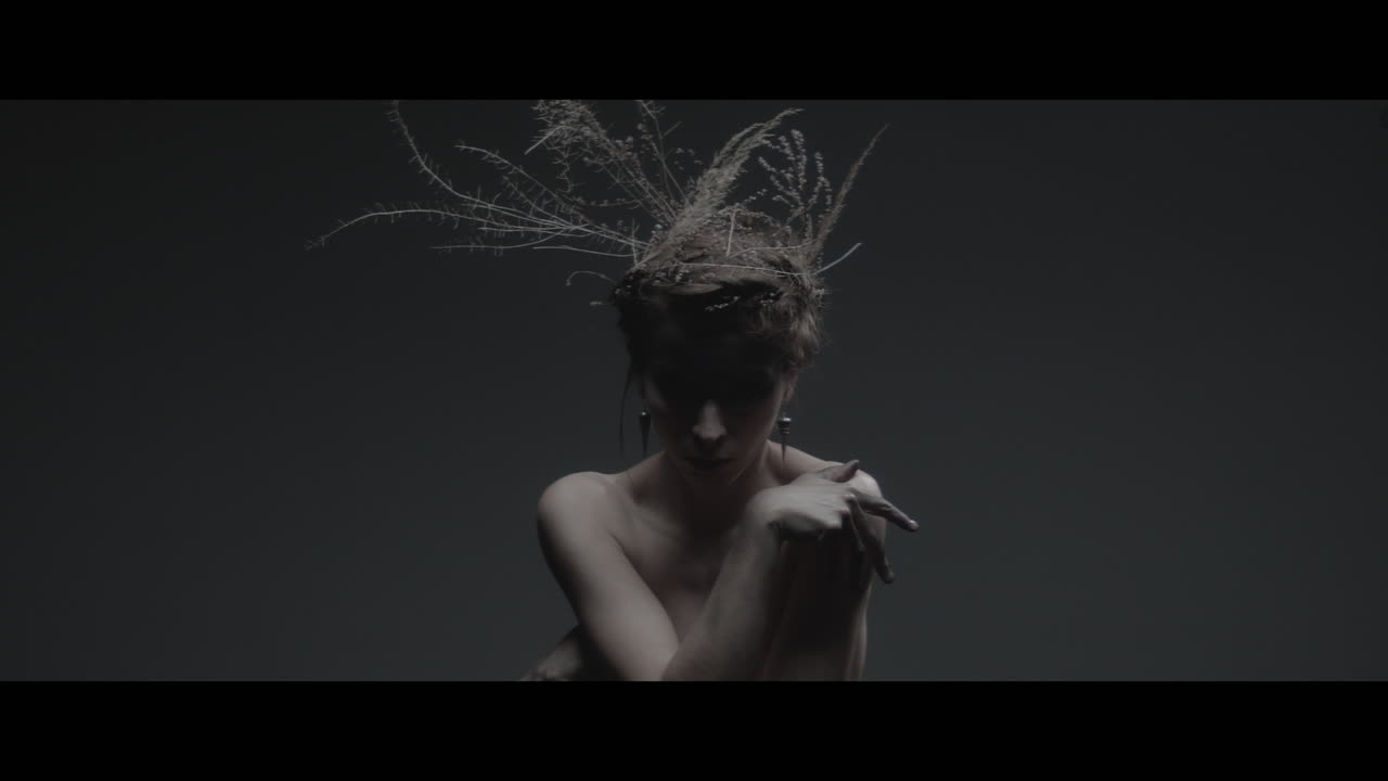 Uma mulher vestida como mãe natureza move-se lentamente em um movimento de dança