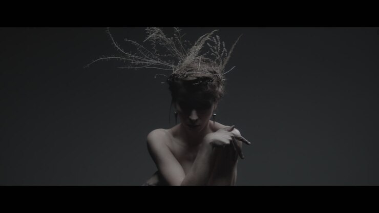 A woman dressed as mother nature moves slowly in a dance-like motion