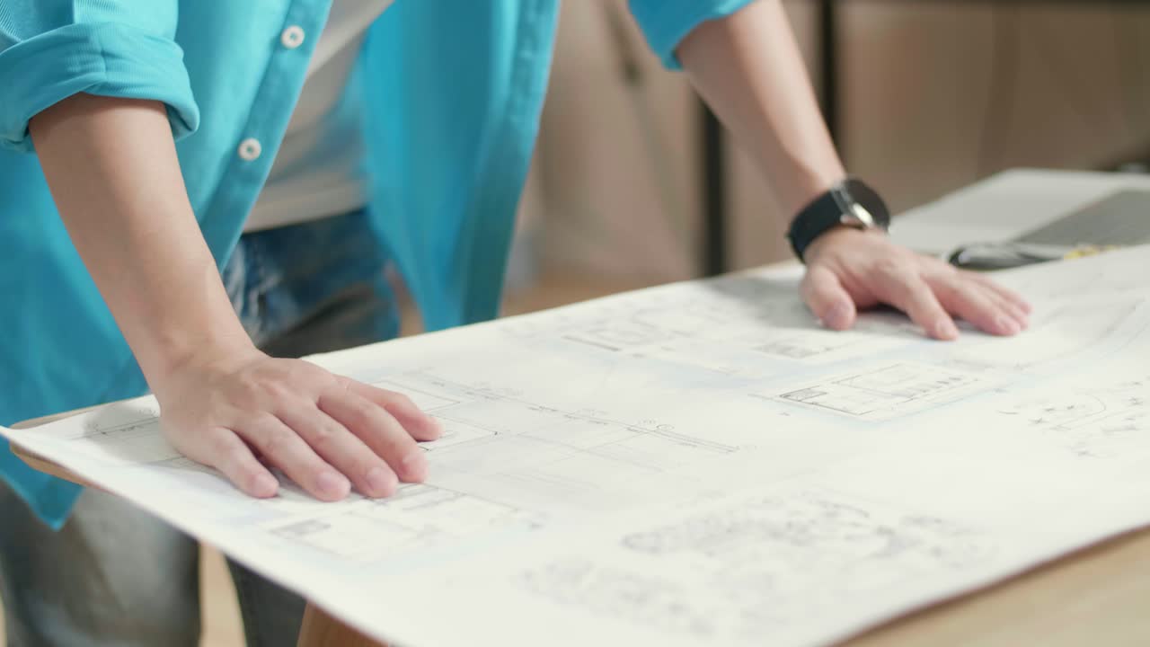 Close Up Of Asian Man Engineer With A Laptop Looking At Blueprint While Working At The Office