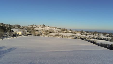 cold snowy winter british patchwork farmland countryside rural scene aerial low to high at sunrise