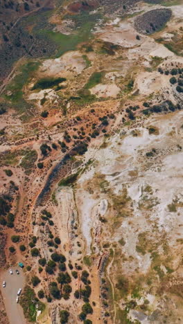 unusual colorful landscape of travertine hot springs, california, usa. few cars parked at the road end. aerial view. vertical video
