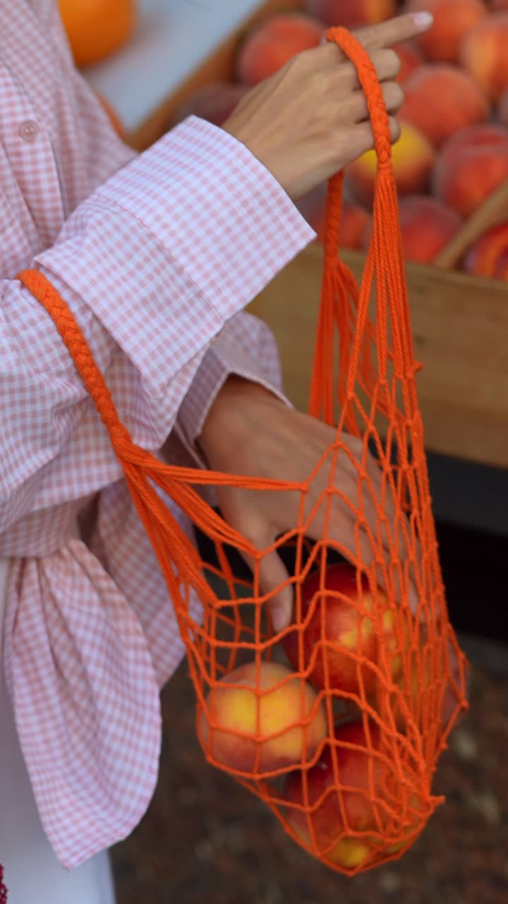 복아 로 가득 찬 메쉬 가방 을 들고 있는 여자