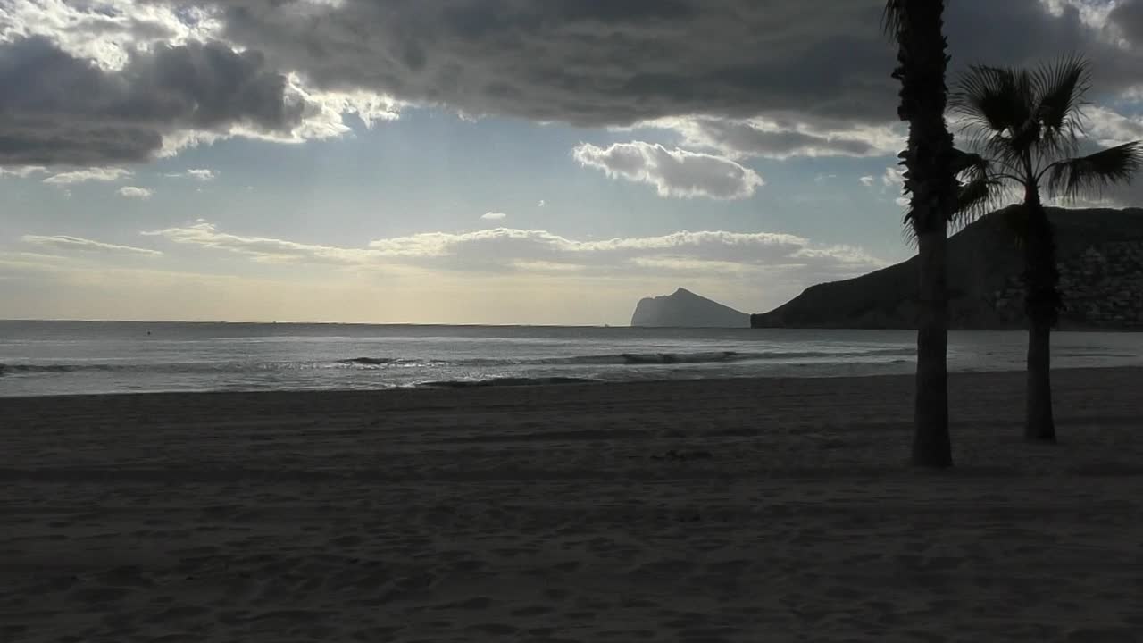Calpe, España. Timelapse en la playa justo antes del atardecer con nubes oscuras pasando