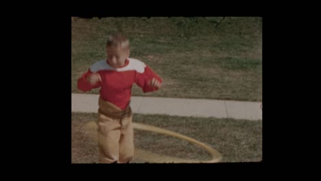 1956 young boy in football uniform does hula hoop