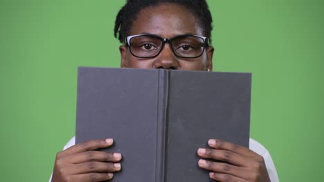 young beautiful african businesswoman covering face with book
