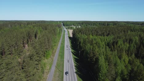 Retreating-aerial-tracks-highway-traffic-thru-vibrant-green-forest