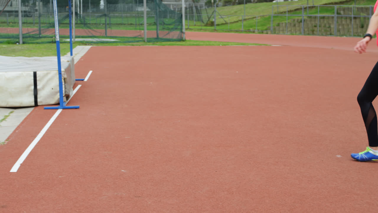 vista lateral de una atleta caucásica practicando el lanzamiento de jabalina en un recinto deportivo 4k
