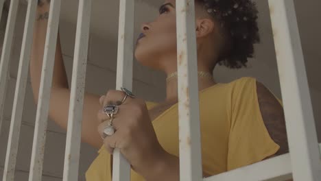 woman with a serious expression examines the iron bars behind which she is trapped and alone