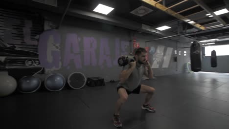 young athletic man doing exercise with a sandbag at the gym