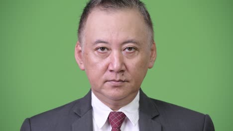 mature japanese businessman against green background