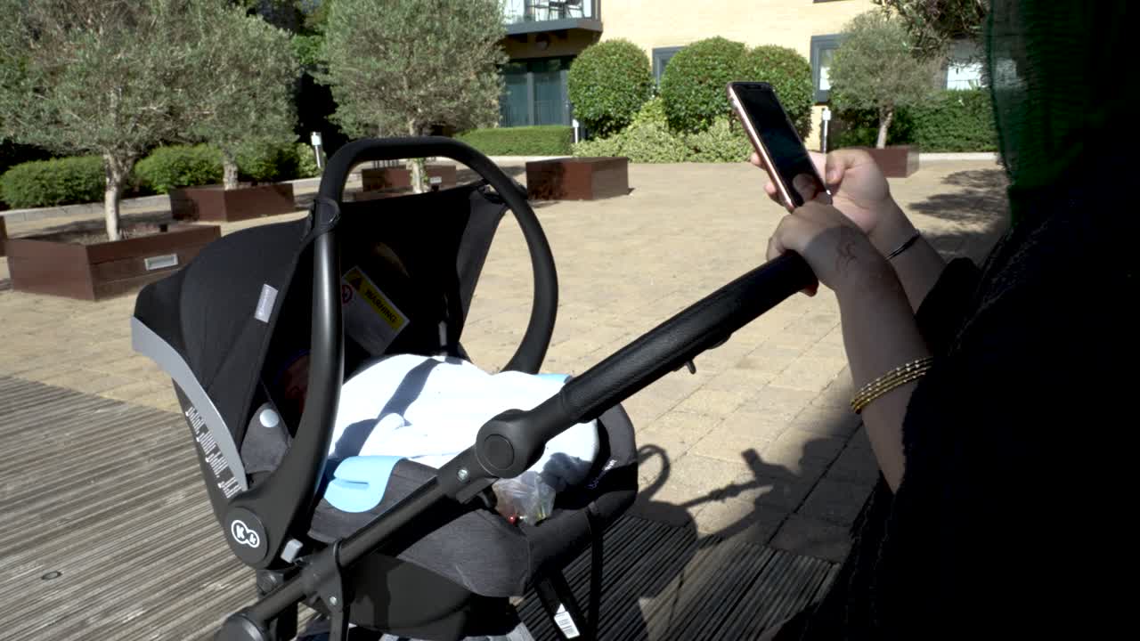 앉아있는 동안 그녀의 전화를 확인하는 아시아 이슬람 어머니