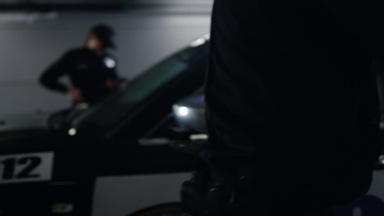 полицейский, привязывающий преступника к патрульной машине.