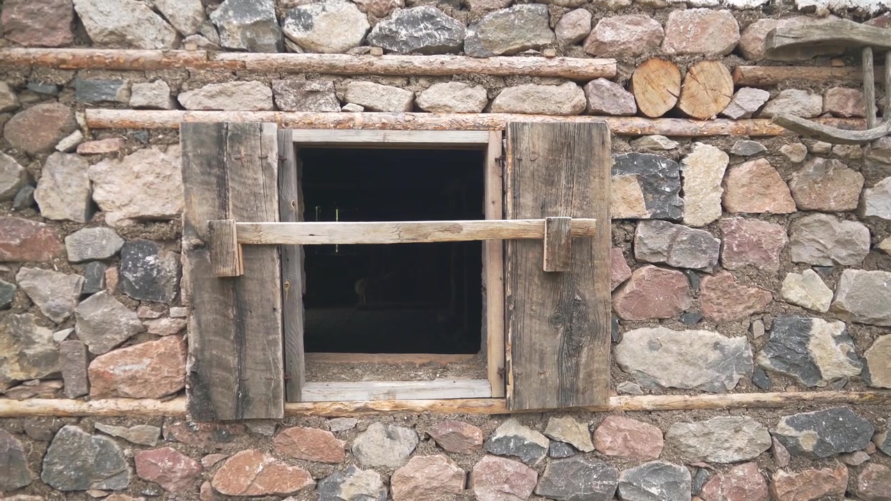 Muro in pietra rustico con finestra in legno e attrezzi agricoli