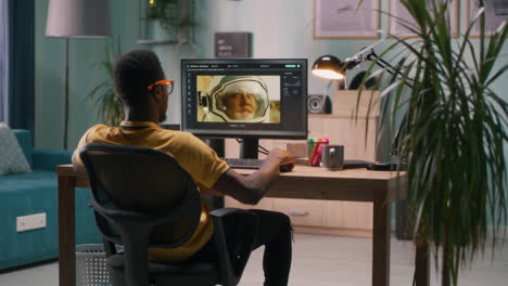 young man editing photos on computer in home office