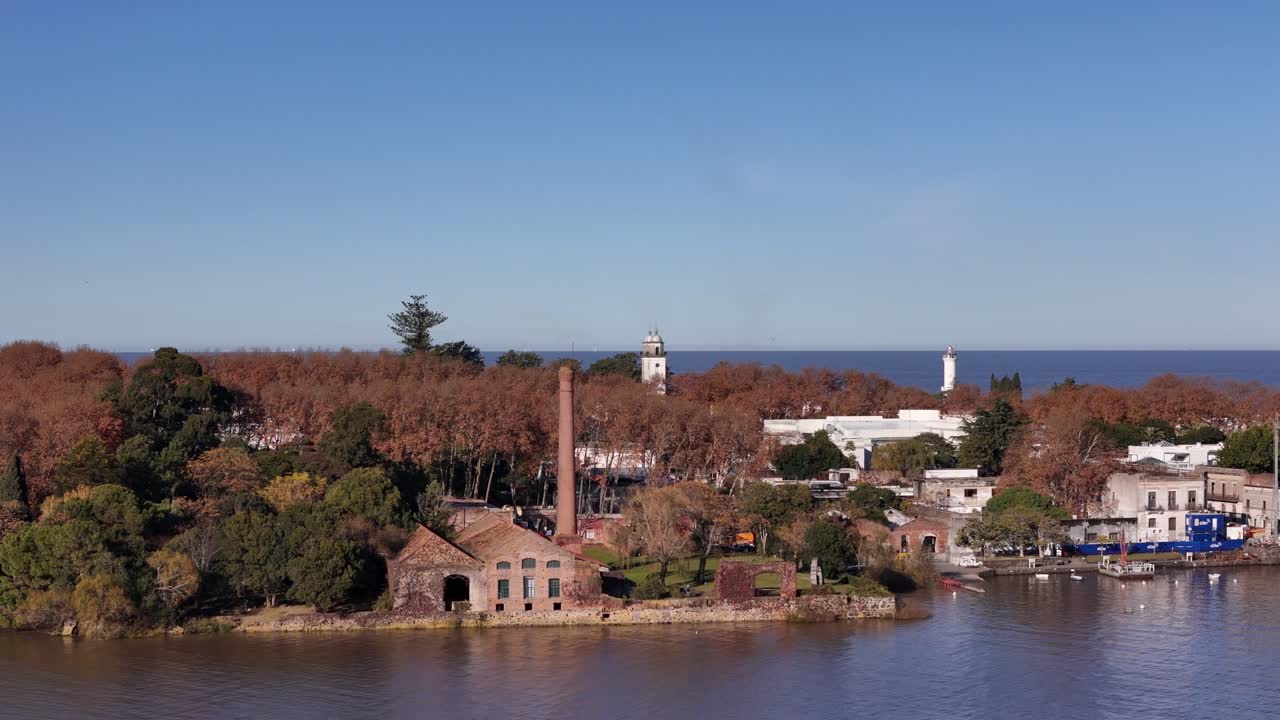 Drone moves forward over the bay toward Colonia del Sacramento, Uruguay. Clear winter morning, passing over Bastión del Carmen with lighthouse and church in view