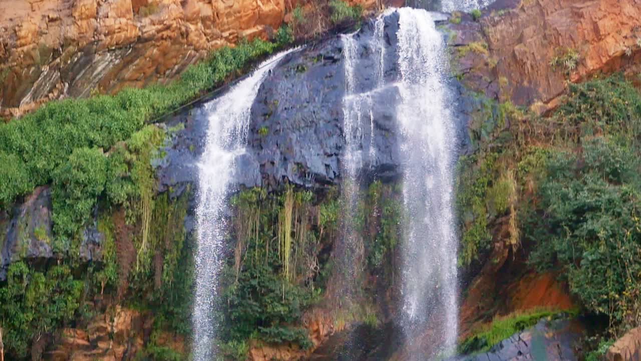 incline hacia abajo, cascada en cámara lenta que fluye de la montaña rocosa hacia el río en el jardín botánico nacional walter sisulu en johannesburgo, sudáfrica