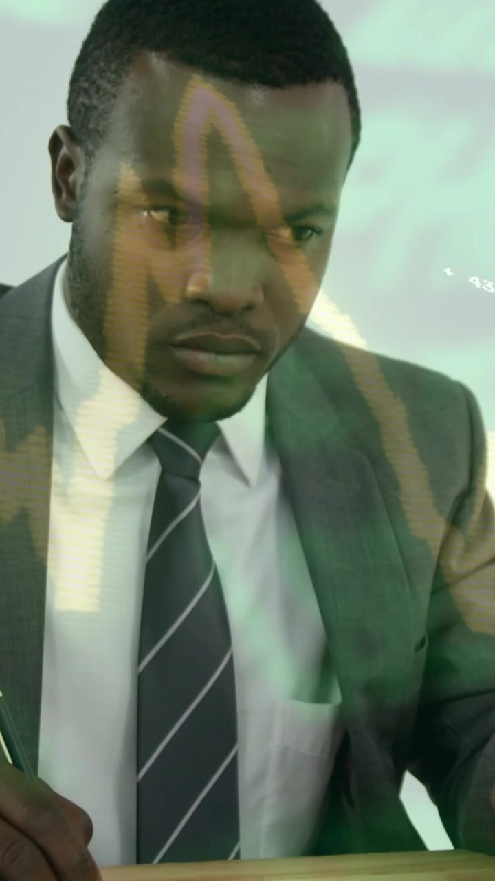 Vertical video: Man placing laptop, writing business notes while green overlay moving, lifting head