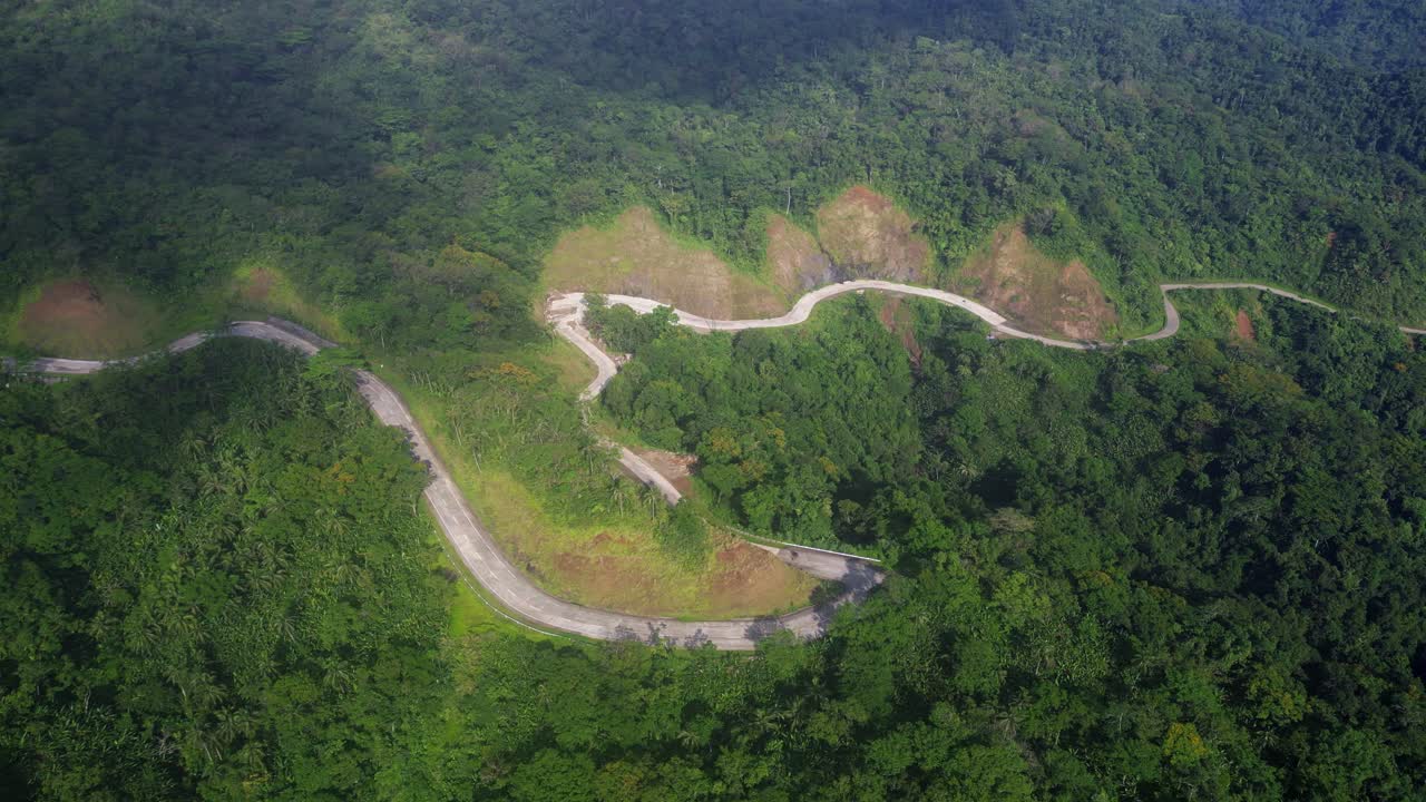 panorámica aérea de la sinuosa carretera de montaña y las sombras de las nubes en el bosque