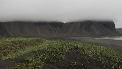 Sanfter-Dolly-Aus-Der-Stimmungsvollen-Und-Dramatischen-Vulkanischen-Küstenlandschaft-Von-Stockksnes-Island-Mit-Bedrohlichen-Bergen-Und-Schwarzem-Vulkansand