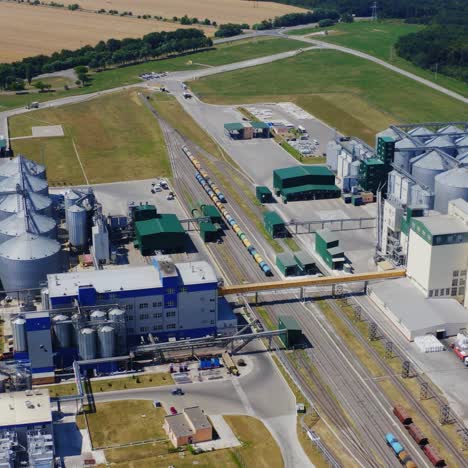 Modern plant with grain elevators on field. Granary for keeping agricultural products. Silver bins for storing crop. Aerial view.