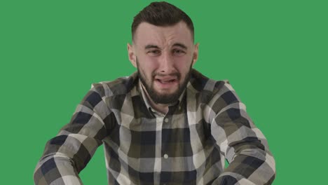 retrato de un hombre guapo caucásico llorando en el fondo de la pantalla verde. chico moreno deprimido frotando los ojos. tristeza, depresión, soledad. chromakey. cine 4k prores hq.