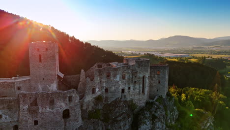 slovak flag waving on the top of the castle on the mountain top. beautiful countryside at the river bank at backdrop. aerial view.