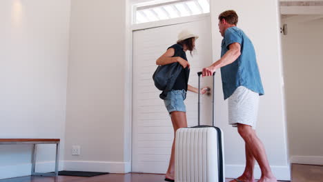 Rear-View-Of-Couple-With-Luggage-Leaving-Home-For-Vacation