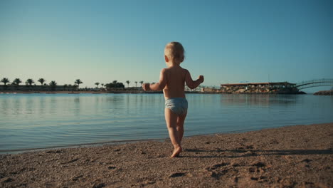 little cute child resting at beautiful sunny resort beach in sunrise time.