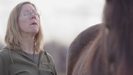 Woman-processes-emotions-standing-next-to-horse-during-equine-therapy,-rack-focus