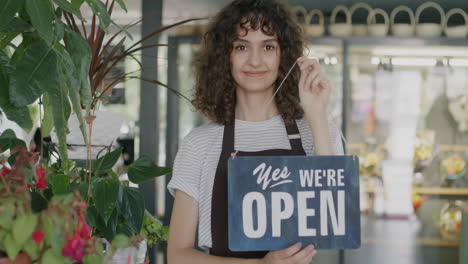 woman in floral shop holding open sign