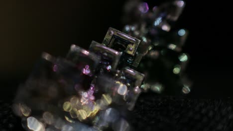 colorful bokeh lights shine on the bismuth crystal isolated on black background -closeup shot